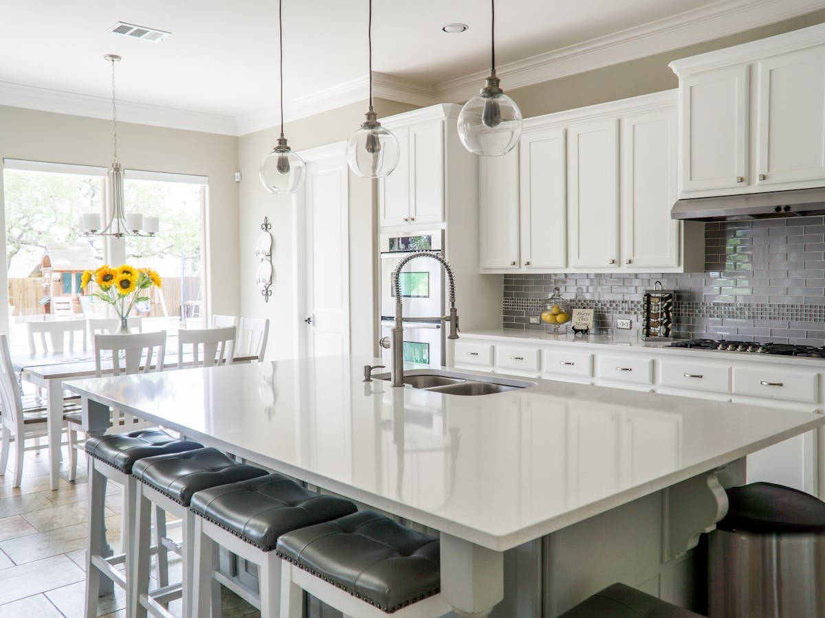 Bright white kitchen with marble island and pendant lighting